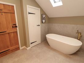 A bathroom with a bathtub and two doors at High Wood Foot in Bampton, Cumbria