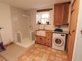 A bathroom with a shower, sink, and washing machine at High Wood Foot, Bampton, Cumbria