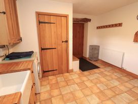 A utility room with a washing machine and sink at High Wood Foot in Bampton, Cumbria