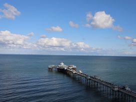 A long pier extending into the sea with buildings on it under a blue sky with clouds