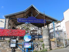 An outdoor tram station with a blue sign reading Great Orme Tramway and a display board near a stone wall in Llandudno