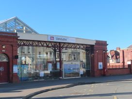 The exterior of Llandudno train station showing glass entrance and red brick walls at 21 Taliesin Street in Llandudno