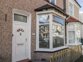 A house entrance with a white door and a bay window beside a small wooden fence at 21 Taliesin Street in Llandudno