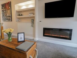 A living room with an electric fireplace and a wall-mounted TV at 21 Taliesin Street in Llandudno
