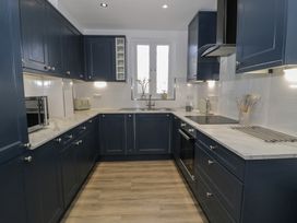 A kitchen with blue cabinets a double sink a microwave and oven at 21 Taliesin Street in Llandudno