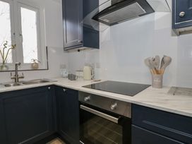 A kitchen with dark blue cabinets a double sink an electric stove oven and cooking utensils at 21 Taliesin Street in Llandudno