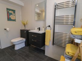 A bathroom with a toilet sink cabinet mirror towel rack and folded towels at 21 Taliesin Street in Llandudno