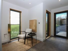 An entrance hall with a chair and lamp at Tithe Barn Lodge Capel Mawr near Malltraeth