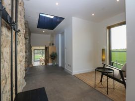 An entrance hall with a stone wall and a skylight at Tithe Barn Lodge Capel Mawr near Malltraeth