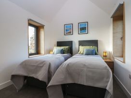A bedroom with two beds and framed pictures at Tithe Barn Lodge Capel Mawr near Malltraeth