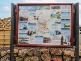 An outdoor information board with a map and various text and images about Llanbedrog