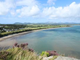 A coastal view of a beach with houses and fields in the background at Hafod in Llanbedrog