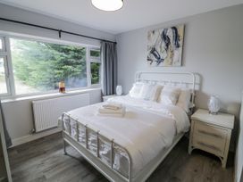 A bedroom with a bed, bedside table, and window at Chillon in South Littleton near Honeybourne