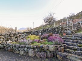 A stone wall with colorful bushes and stone steps leading uphill at Tyn Y Graig in Fairbourne