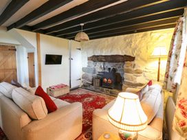 A sitting room with two sofas a lit fireplace and a wall mounted television at Tyn Y Graig in Fairbourne