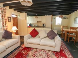 A living room with beige sofas and cushions next to a dining table and kitchen at Tyn Y Graig in Fairbourne