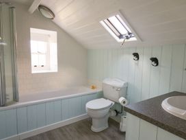 A bathroom with a bathtub a toilet a sink and two fish-shaped hooks on the wall at Tyn Y Graig in Fairbourne