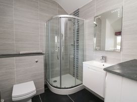 A bathroom with a corner shower enclosure a toilet a sink with a cabinet and a mirror at Tyn Y Graig in Fairbourne