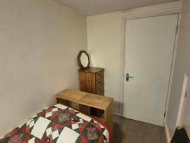 A bedroom with a bed and a dresser at Garden Flat in Porthmadog