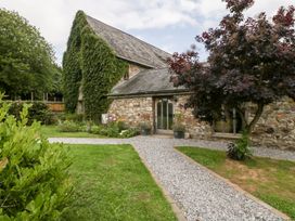 A stone cottage with ivy on the wall gravel paths and a tree in the garden at Mistletoe Cottage in Kemeys Commander near Usk