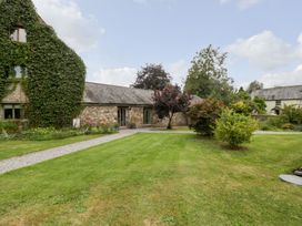 A garden with grass lawn bushes and a stone building covered in ivy at Mistletoe Cottage in Kemeys Commander near Usk