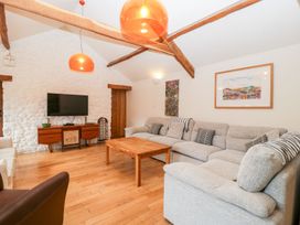 A living room with a large sectional sofa wooden coffee table and wall-mounted TV at Mistletoe Cottage Kemeys Commander near Usk