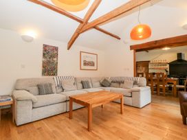 A living room with a grey sectional sofa wooden coffee table and exposed ceiling beams at Mistletoe Cottage in Kemeys Commander near Usk
