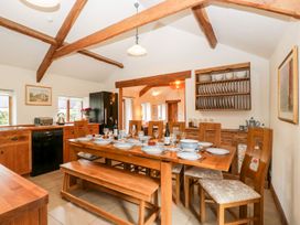 A kitchen with a wooden dining table set for a meal with chairs and a bench at Mistletoe Cottage in Kemeys Commander near Usk