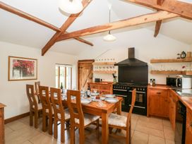 A kitchen dining area with a wooden table set for six chairs and wooden cabinets at Mistletoe Cottage in Kemeys Commander near Usk
