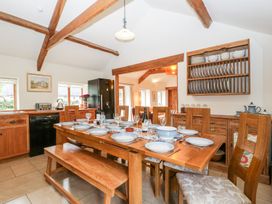 A kitchen dining area with a wooden table set with plates glasses and cutlery and wooden chairs and a bench at Mistletoe Cottage Kemeys Commander near Usk