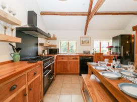 A kitchen with wooden cabinets a dining table set with plates glasses and cutlery at Mistletoe Cottage in Kemeys Commander near Usk