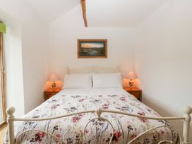 A bedroom with a double bed and floral bedding with two bedside tables and lamps and a framed picture on the wall at Mistletoe Cottage Kemeys Commander near Usk