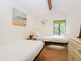 A bedroom with two single beds a wooden cabinet a small bedside table and a window at Mistletoe Cottage in Kemeys Commander near Usk