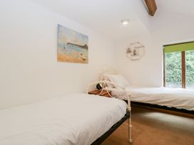 A bedroom with two single beds a wooden nightstand a wall painting and a window with a green blind at Mistletoe Cottage Kemeys Commander near Usk