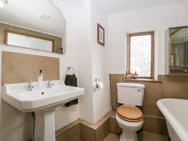 A bathroom with a pedestal sink a toilet with wooden seat a window with patterned glass and a bathtub at Mistletoe Cottage in Kemeys Commander near Usk