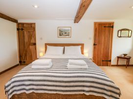 A bedroom with a wicker bed two wooden doors and a small table with a bowl at Mistletoe Cottage in Kemeys Commander near Usk