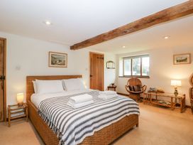 A bedroom with a large bed two chairs a window and wooden furniture with a striped blanket at Mistletoe Cottage in Kemeys Commander near Usk