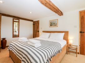 A bedroom with a wicker bed striped blanket folded towels mirror wooden doors and a bedside table lamp at Mistletoe Cottage Kemeys Commander near Usk