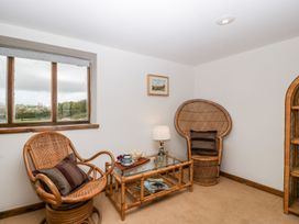 A sitting area with rattan chairs a glass coffee table a lamp and a window at Mistletoe Cottage in Kemeys Commander near Usk
