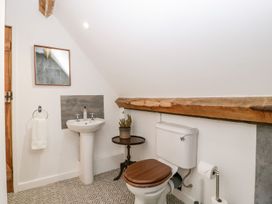 A bathroom with a toilet a sink a mirror and a small table with a plant at Mistletoe Cottage in Kemeys Commander near Usk