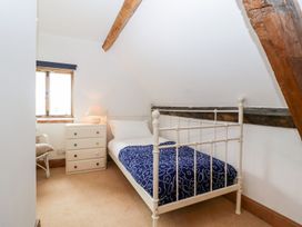 A bedroom with a single bed a dresser with a lamp a window and exposed wooden beams at Mistletoe Cottage in Kemeys Commander near Usk