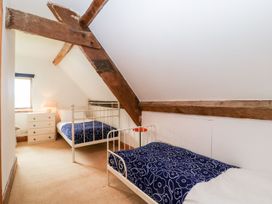 A bedroom with two single beds with blue floral blankets wooden beams and a chest of drawers with a lamp at Mistletoe Cottage in Kemeys Commander near Usk