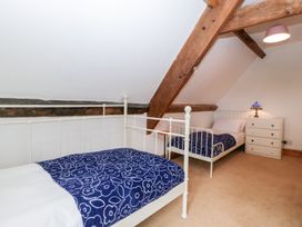 A bedroom with two single beds with blue floral blankets and a white chest of drawers with a lamp at Mistletoe Cottage in Kemeys Commander near Usk