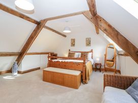A bedroom with wooden bed frame bench mirror and vase under exposed wooden beams at Mistletoe Cottage in Kemeys Commander near Usk