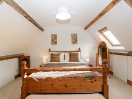 A bedroom with a wooden bed and pillows with lamps on bedside tables at Mistletoe Cottage Kemeys Commander near Usk