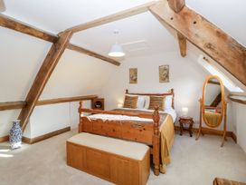 A bedroom with a wooden bed bench mirror and exposed beams at Mistletoe Cottage in Kemeys Commander near Usk