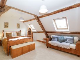 A bedroom with a wooden bed bench wicker sofa and slanted windows at Mistletoe Cottage in Kemeys Commander near Usk