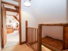 A hallway with wooden railing and a bedroom visible through an open door at Mistletoe Cottage in Kemeys Commander near Usk