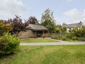 A garden with a gravel path stone shed and green plants at Mistletoe Cottage in Kemeys Commander near Usk