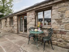 An outdoor seating area with a small round table and two chairs beside a stone wall at Mistletoe Cottage Kemeys Commander near Usk